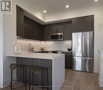 Toronto (Rockcliffe-Smythe) townhouse for rent - A modern kitchen with dark wood cabinets and stainless steel appliances.