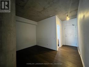 Toronto (Moss Park) condo for rent - A room with a concrete pillar and wooden flooring.