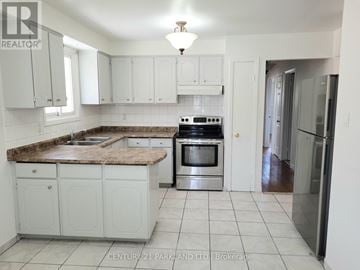 Brampton (Brampton North) apartment for rent - A kitchen with white cabinets and a granite countertop.