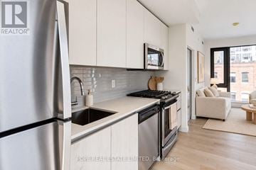 Toronto (Waterfront Communities) condo for rent - A modern kitchen with a refrigerator, microwave, and stove top oven.