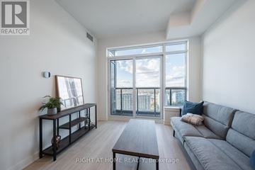 Vaughan (Brownridge) condo for rent - A living room with a grey sofa and a large window.
