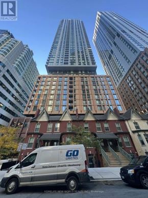 Toronto (Waterfront Communities) condo for rent - A white van with the logo "GO Logistics" is parked in front of a building with a sign that reads "HOMELIFE NEW WORLD REALTY INC. Brokerage."