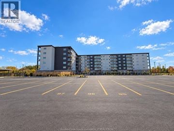 Windsor apartment for rent - A parking lot with a large building in the background.
