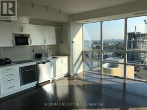 Toronto (Moss Park) condo for rent - A well-lit kitchen with a view of the cityscape outside the large windows.