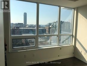 Toronto (Moss Park) condo for rent - A room with a large window overlooking a cityscape.