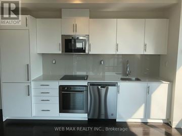 Toronto (Moss Park) condo for rent - A kitchen with white cabinets and a black countertop.