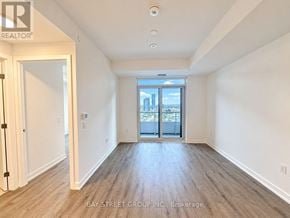 Vaughan (Vaughan Corporate Centre) condo for rent - A spacious room with wooden floors and a view of the city through the glass doors.