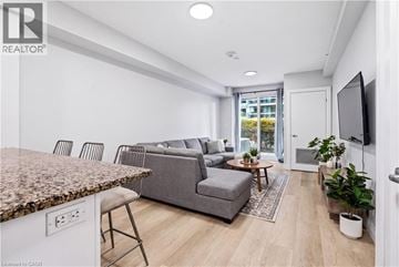 Guelph condo for rent - A living room with a grey couch and a brown granite counter.