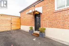 Toronto (Clairlea-Birchmount) apartment for rent - A red brick house with a black door and a wooden fence.