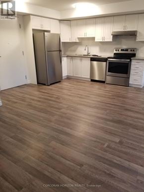 Tillsonburg house for rent - A kitchen with white cabinets and a wood floor.