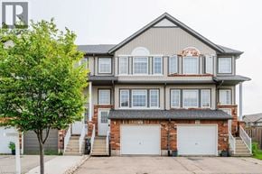 Kitchener townhouse for rent - A two-story house with a garage and a tree in front.