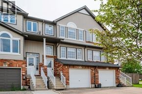 Kitchener townhouse for rent - A large house with a garage and a tree in front.