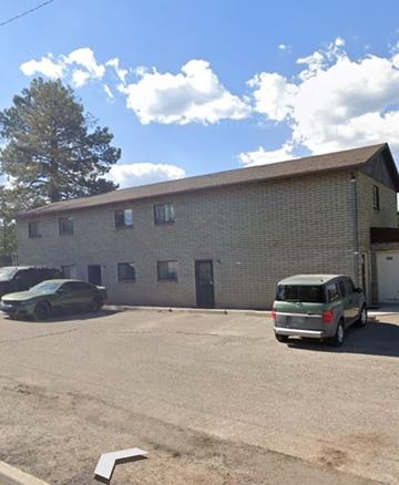 Flagstaff apartment for rent - A green van is parked in a lot in front of a brick building.