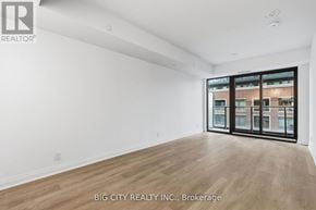 Toronto (Thorncliffe Park) condo for rent - A spacious room with wooden flooring and a large window overlooking a cityscape.
