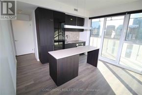Toronto (Waterfront Communities) condo for rent - A modern kitchen with dark wood floors and a large island.