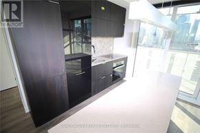 Toronto (Waterfront Communities) condo for rent - A modern kitchen with dark wood cabinets and a large window.