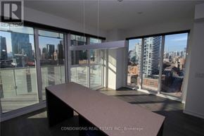 Toronto (Waterfront Communities) condo for rent - A large, empty room with a view of the city through floor-to-ceiling windows.