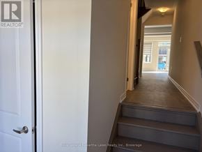 Kawartha Lakes (Lindsay) townhouse for rent - A hallway with a white door and a set of stairs leading to a balcony.