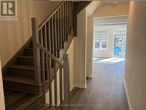 Kawartha Lakes (Lindsay) townhouse for rent - A staircase with a wooden handrail and steps leading to a bright room with a window.