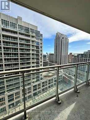 Toronto (Niagara) condo for rent - A balcony with a glass railing overlooks a cityscape.