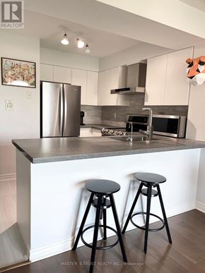 Toronto (Willowdale East) condo for rent - A kitchen with a refrigerator, oven, and two stools.