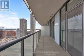 Toronto (Waterfront Communities) condo for rent - A balcony with glass railings overlooks a cityscape.