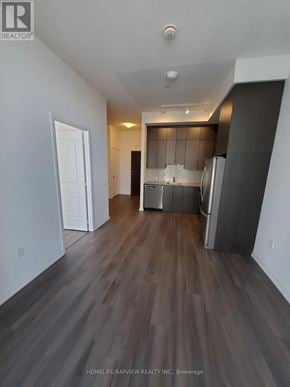 Toronto (Henry Farm) condo for rent - A spacious room with wooden flooring and a kitchen area in the background.