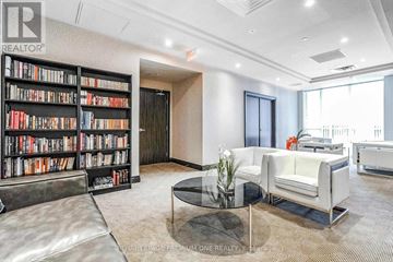 Toronto (Islington-City Centre West) condo for rent - A living room with a glass coffee table and a bookshelf filled with books.