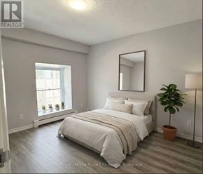 Guelph (Downtown) multi-family for rent - A bedroom with a bed, a mirror, and a potted plant.