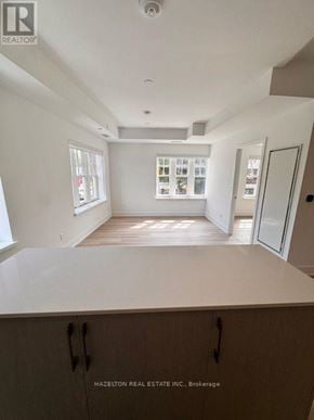 Toronto (Yonge-Eglinton) condo for rent - A real estate listing photo of a white kitchen with wood floors and cabinets.