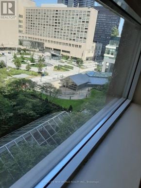 Toronto (Bay Street Corridor) condo for rent - A view from a window looking out at a cityscape with buildings and a parking lot.