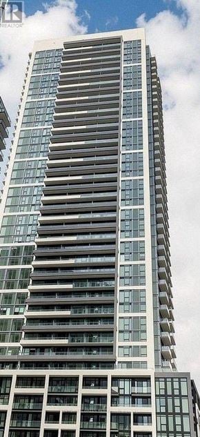 Brampton (Fletcher's Creek South) condo for rent - A tall building with many windows is shown against a cloudy sky.