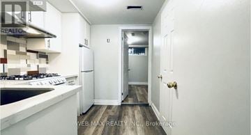 Toronto (South Parkdale) townhouse for rent - A white kitchen with a stove top oven and a refrigerator.