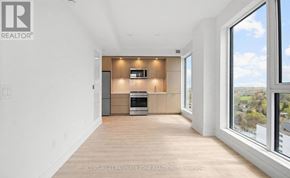 Toronto (Islington-City Centre West) condo for rent - A spacious, well-lit room with a kitchen area and a large window overlooking a landscape.