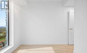 Toronto (Islington-City Centre West) condo for rent - A white room with a door and a window overlooking a tree-filled landscape.