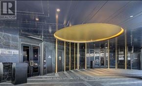 Toronto (Waterfront Communities) condo for rent - The entrance to a building with a large golden arch and a sign that reads "RE/MAX REALTY SPECIALISTS INC, Brokerage".