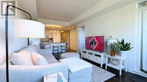 Oakville (Br Bronte) condo for rent - A living room with a grey couch, a white coffee table, and a red painting on the wall.