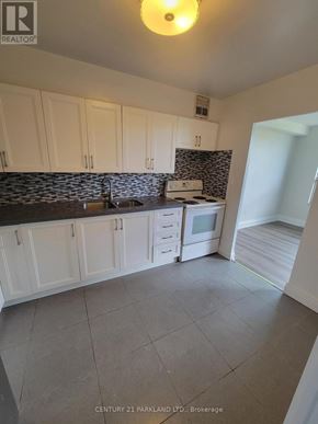 Toronto (Flemingdon Park) condo for rent - A kitchen with white cabinets and a black counter top.