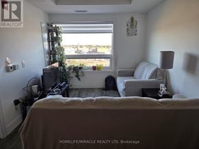 Brantford condo for rent - A living room with a couch, a chair, a television, and a window with a view of the outdoors.