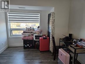 Brantford condo for rent - A room with a window, a bed, a chair, a desk, and a suitcase.