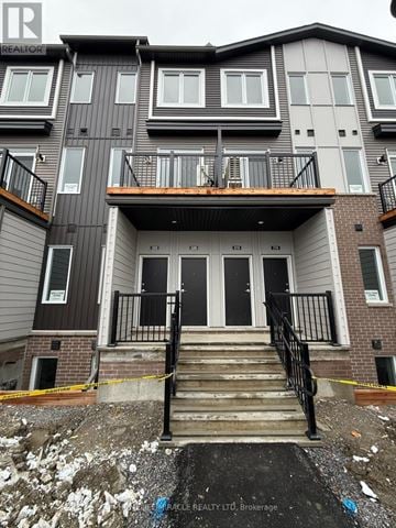 Ottawa townhouse for rent - A multi-story building with a balcony and stairs leading to the entrance.