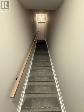 Ottawa townhouse for rent - A staircase with a wooden handrail leading to a door at the end.