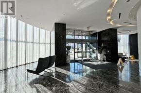 Mississauga (City Centre) condo for rent - A modern living room with a black sofa and a large window.