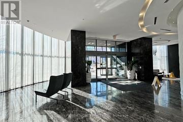 Mississauga (City Centre) condo for rent - A modern living room with a black sofa and a large window.