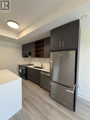 St. Catharines (Oakdale) townhouse for rent - A modern kitchen with a refrigerator, microwave, and oven.