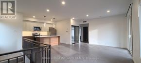 Ottawa multi-family for rent - A spacious, empty living room with a kitchen area in the background.