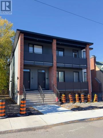 Ottawa multi-family for rent - A two-story building with a balcony and a black awning.
