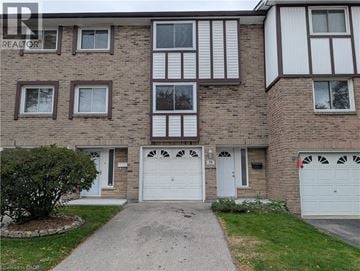 Hamilton townhouse for rent - A brown brick building with white garage doors and windows.