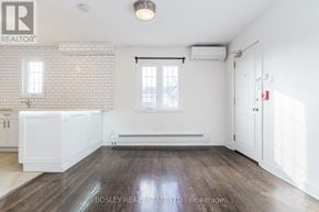 Toronto (High Park-Swansea) multi-family for rent - A spacious room with wooden flooring and white walls.
