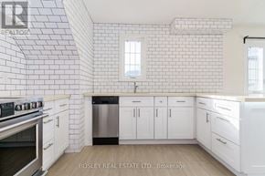 Toronto (High Park-Swansea) multi-family for rent - A white kitchen with a stove top oven and a dishwasher.